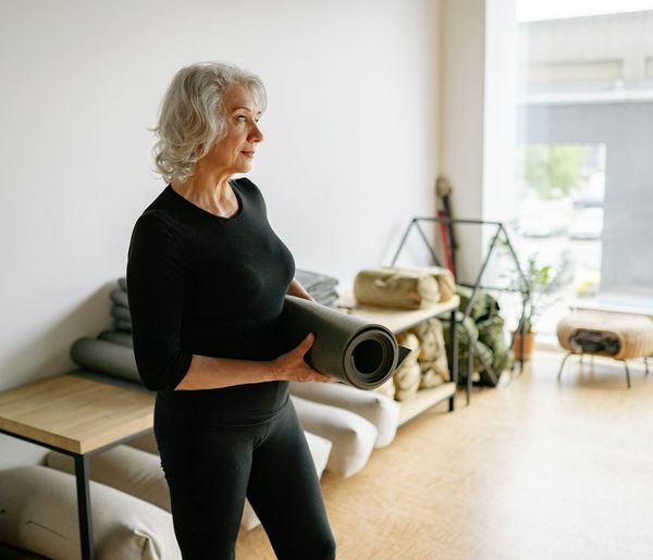 Person in a flowing yoga pose in a spacious bright room.